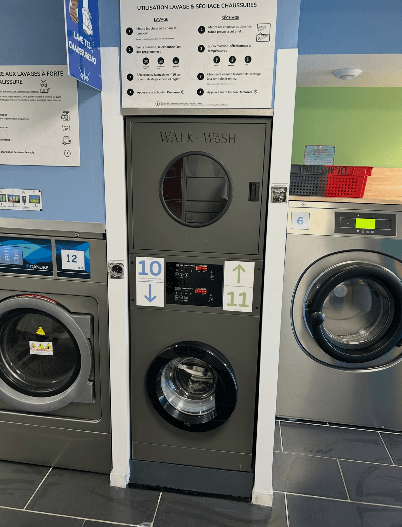 Màquina Walk & Wash, amb les portes tancades, entre les màquines de la bugaderia